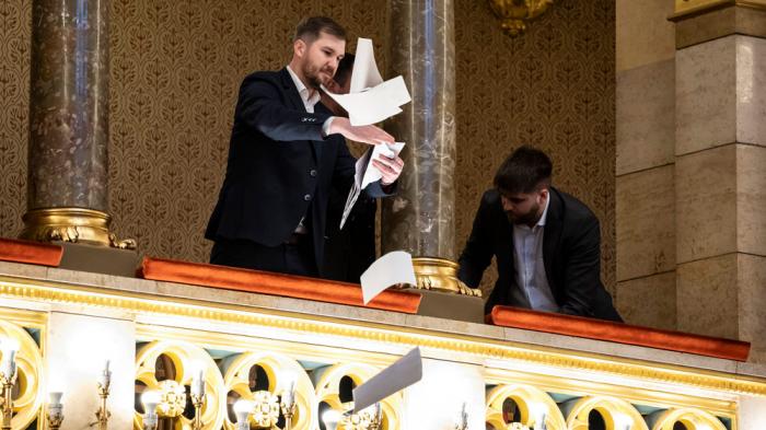 Ferenc Gelencser of Momentum, left, throws pamphlets from the balcony during the plenary session of the Hungarian parliament in Budapest, Hungary, Tuesday, March 18, 2025