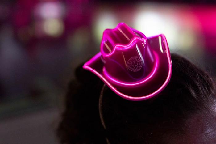 A volunteer wears a neon pink cowboy hat a during a Pink Pony Prom" organized by the Sexual & Gender Minority Youth Resource Center, part of New Avenues for Youth, a nonprofit dedicated to ending youth homelessness, on Friday, May 30, 2025, in Portla