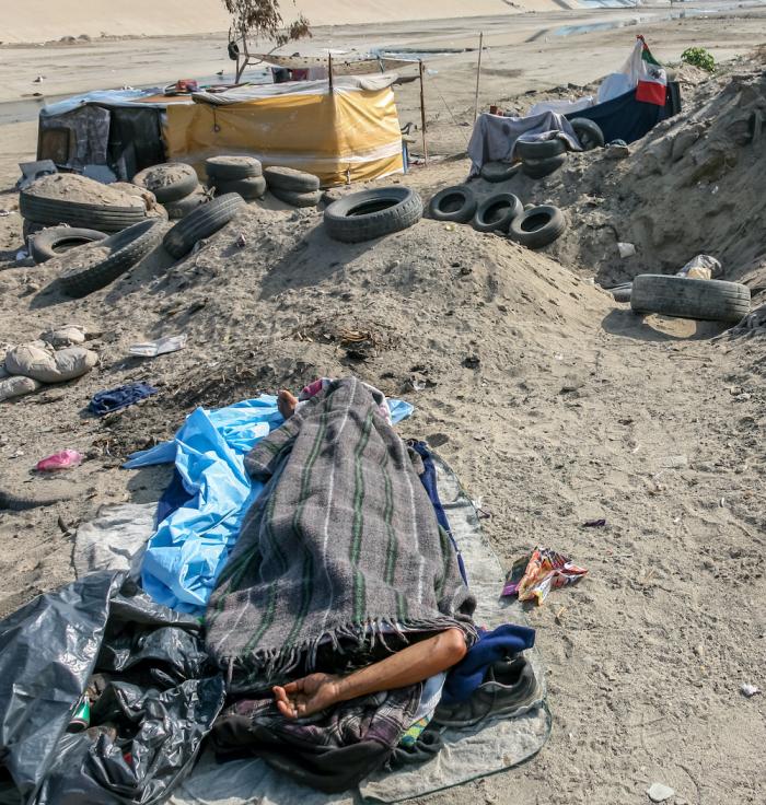 A migrant sleeps in a canal near the wall that separates and protects the border line between the United States and Mexico and San Ysidro border port.