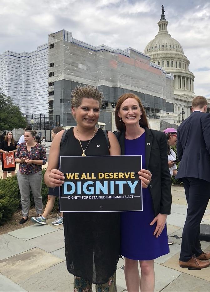 (l to r) Raiza Hernandez and Tess Feldman holding a sign in support of the Dignity for Detained Immigrants bill.