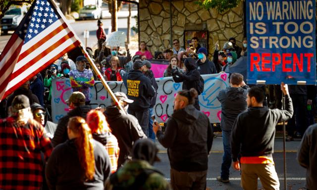 Protesters and supporters of a drag queen story time event square off in front of Old Nick's pub in Eugene, Ore., Sunday Oct. 23, 2022