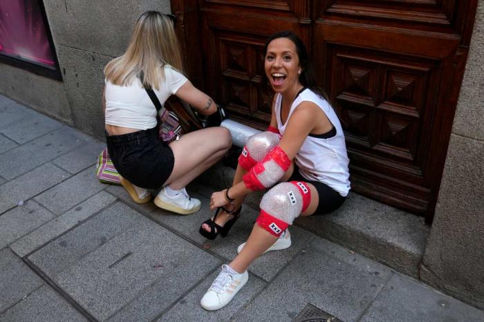 A participant reacts to photographers while changing into high heel shoes before the pride week annual high heels race in the Chueca district, a popular area for the gay community in Madrid, Spain, Thursday, July 4, 2024