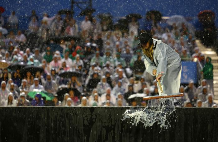 A worker sweeps rain water at the Trocadero during the opening ceremony of the 2024 Summer Olympics, Friday, July 26, 2024 in Paris, France. (Stephanie Lecocq/Pool Photo via AP)