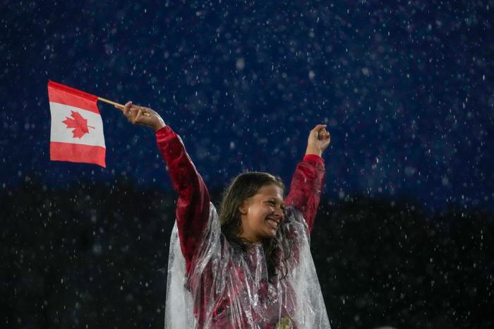 A Canadian athlete reacts while participating in the opening ceremony of the 2024 Summer Olympics, Friday, July 26, 2024, in Paris, France. (AP Photo/Andy Wong)