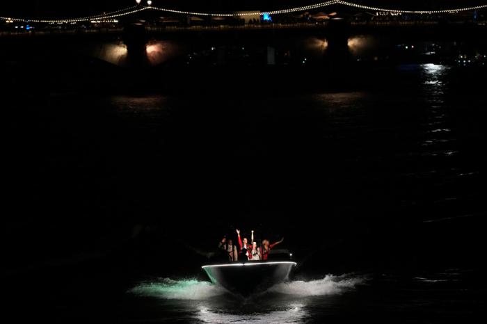 Rafael Nadal carries the Olympic flame flanked by Serena Williams, right, in Paris, France, during the opening ceremony of the 2024 Summer Olympics, Friday, July 26, 2024. (AP Photo/Christophe Ena)