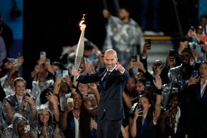 Zinedine Zidane carries the torch in Paris, France, during the opening ceremony of the 2024 Summer Olympics, Friday, July 26, 2024. (AP Photo/Natacha Pisarenko)