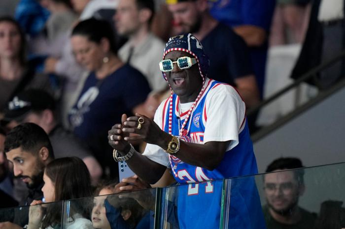 Flavor Flav celebrates after a women's Water Polo Group B preliminary match between USA and Greece at the 2024 Summer Olympics, Saturday, July 27, 2024, in Saint-Denis, France. (AP Photo/Luca Bruno)