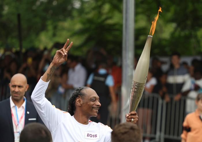 Snoop Dogg carries the Olympic torch at the 2024 Summer Olympics, Friday, July 26, 2024, in Saint-Denis, outside Paris, France. (AP Photo/Aurelien Morissard)