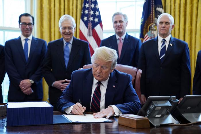 President Donald Trump signs the coronavirus stimulus relief package, at the White House, Friday, March 27, 2020, in Washington, as from left, Treasury Secretary Steven Mnuchin, Senate Majority Leader Mitch McConnell of Ky., House Minority Kevin McCarthy of Calif., and Vice President Mike Pence, look on