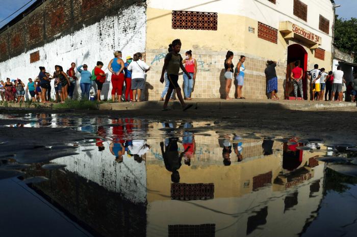 Neighbors line up for free food staples outside Santa Ana primary school in Asuncion, Paraguay.