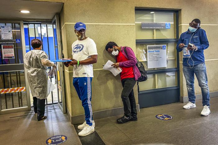 People who were just tested for COVID-19 wait in line to make payment for the test at a private laboratory in Johannesburg, South Africa.