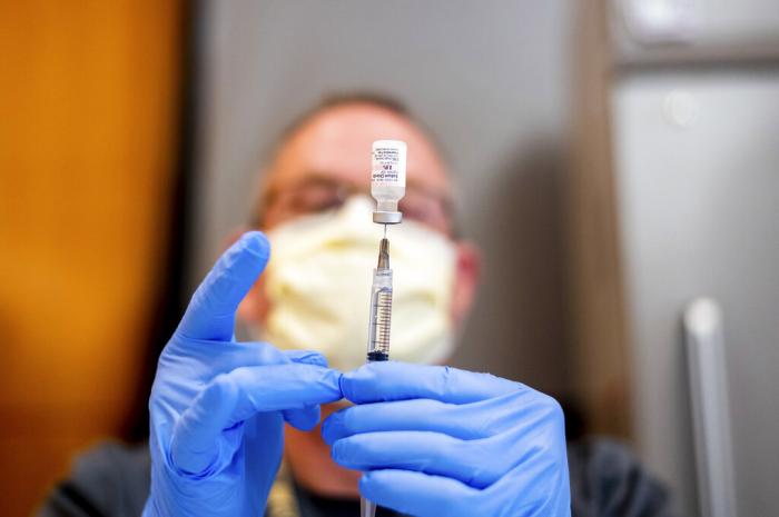 A pharmacist draws saline while preparing a dose of Pfizer's COVID-19 vaccine in Sacramento, Calif.