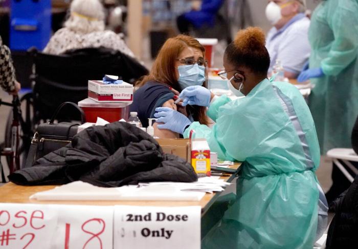 Registered nurse, Adele Prieto, left, receives her second dose of the COVID-19 vaccine from Lesia Turner at the Dallas County mass vaccination site at Fair Park in Dallas.