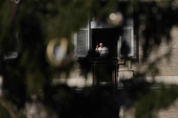 Pope Francis, framed by the Vatican Christmas tree, salutes pilgrims and faithful during the Angelus noon prayer from the window of his studio overlooking St.Peter's Square, at the Vatican.