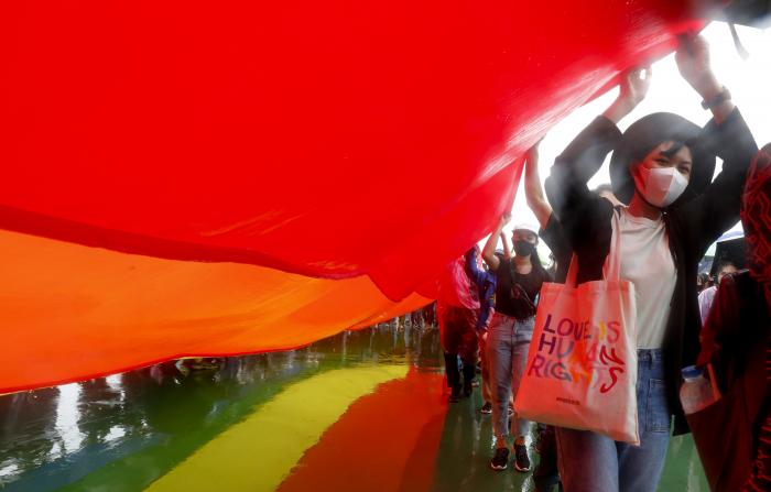 Pro-democracy LGBTQ activists carry a huge rainbow flag in the rain as they gather in front of the Grand Palace in Bangkok, Thailand.
