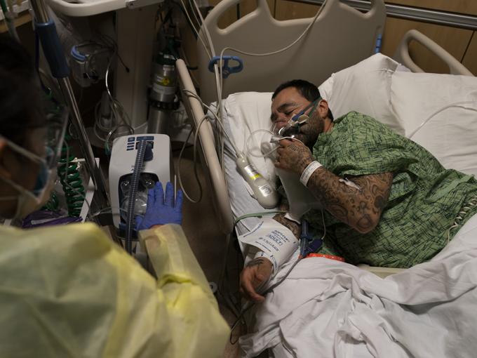 Registered nurse Emily Yu gestures to Paul Altamirano, 50, while treating him in a COVID-19 unit at Providence Holy Cross Medical Center in Los Angeles, Monday, Dec. 13, 2021