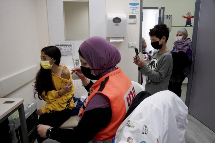 N'amah Yetzhak Abohaikal, a volunteer with the women's unit of United Hatzalah emergency service, prepares administer the COVID-19 vaccine to a teen girl.