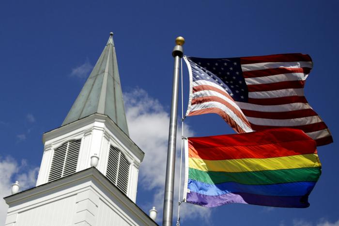 A gay pride rainbow flag flies along with the U.S. flag in front of the Asbury United Methodist Church in Prairie Village, Kan.