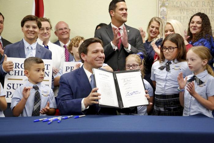 Florida Gov. Ron DeSantis displays the signed Parental Rights in Education, aka the Don't Say Gay bill, flanked by elementary school students during a news conference