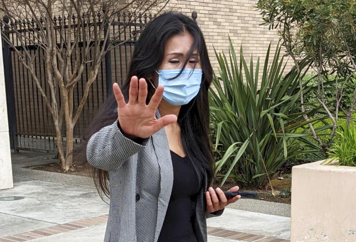 Julie Lee Choi waves off reporters outside Santa Clara Superior Court in San Jose, Calif.