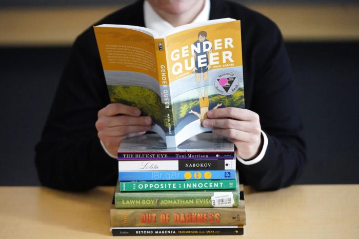 Amanda Darrow, director of youth, family and education programs at the Utah Pride Center, poses with books on Dec. 16, 2021, that have been the subject of complaints from parents in Salt Lake City. 