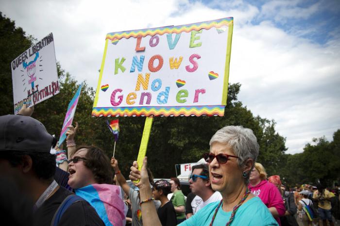 Barbara Dale, from Atlanta, mother of a transgender child, waves sign reading "Love Knows No Gender" at Gay Pride Transgender March at Piedmont Park in the city's Midtown District in Atlanta, Ga.