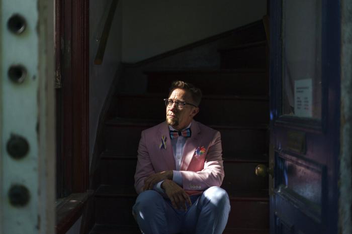 Scout, a transgender man who uses one name, stands in the entrance to his home in Providence, R.I.