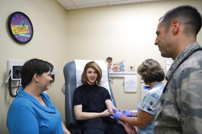 Dr. David Klein, right, an Air Force Major and chief of adolescent medicine at Fort Belvoir Community Hospital, listens as Amanda Brewer, left, speaks with her daughter, Jenn Brewer, 13, as the teenager has blood drawn during a monthly appointment for monitoring her treatment at the hospital in Fort Belvoir, Va.