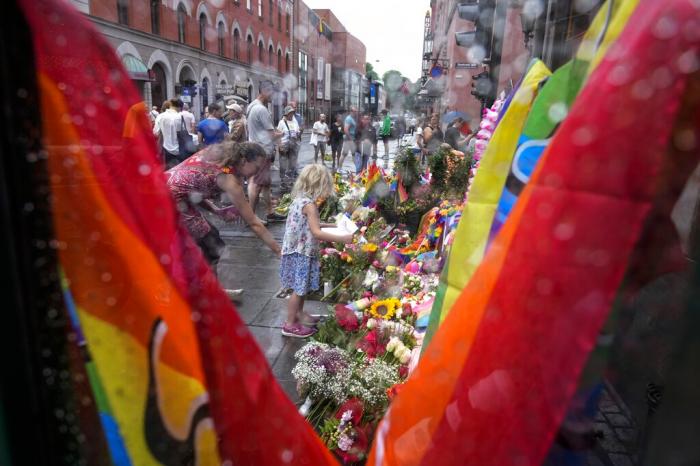 People lay flowers under the rain at the scene of a shooting in central of Oslo, Norway.