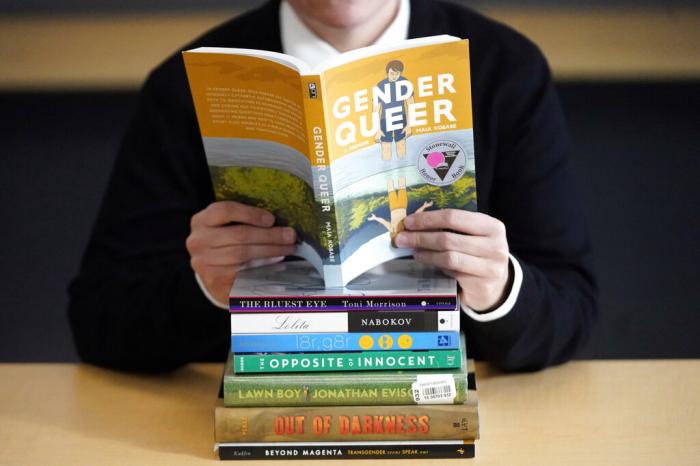 Amanda Darrow, director of youth, family and education programs at the Utah Pride Center, poses with books that have been the subject of complaints from parents in recent weeks on Thursday, Dec. 16, 2021, in Salt Lake City.