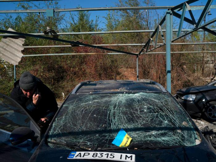 Dmytro Pocishchuk checks his car, which was damaged after a Russian attack in Zaporizhzhia, Ukraine, Saturday, Oct. 15, 2022. (AP Photo/Leo Correa)
