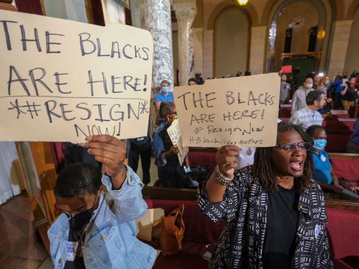 People hold signs and shout slogans before the starting the Los Angeles City Council meeting on Tuesday, Oct. 11, 2022 in Los Angeles.