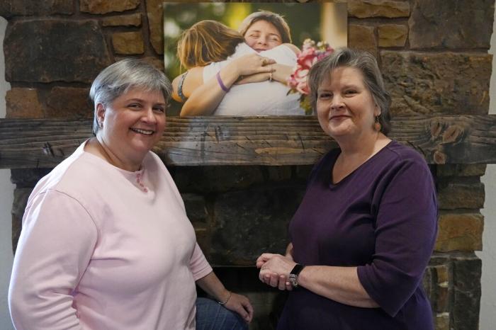 Sharon Bishop-Baldwin, left, and Mary Bishop-Baldwin, right, pose for a photo with a photograph from their wedding day, in their home Tuesday, Nov. 29, 2022, in Broken Arrow, Okla.