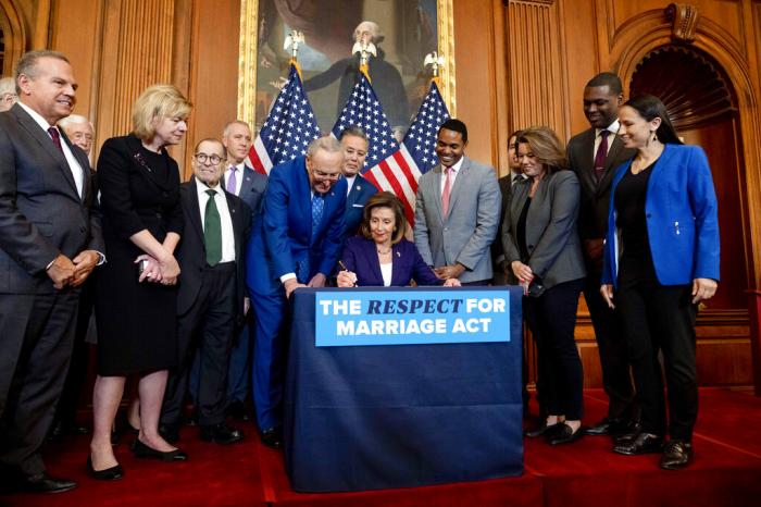 House Speaker Nancy Pelosi of Calif., accompanied by Senate Majority Leader Sen. Chuck Schumer of N.Y., left, and other members of Congress, signs the H.R. 8404, the Respect For Marriage Act, on Capitol Hill in Washington.