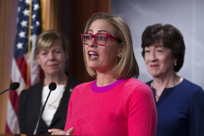 Sen. Kyrsten Sinema, D-Ariz., flanked by Sen. Tammy Baldwin, D-Wis., left, and Sen. Susan Collins, R-Maine, speaks to reporters following Senate passage of the Respect for Marriage Act, at the Capitol in Washington.