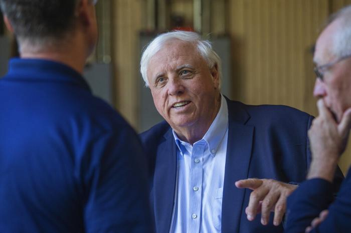 Gov. Jim Justice, center, speaks to Merl Wooten, owner of Wooten Machine Co., left, and Dr. Matthew Rohrbach while visiting community members on May 9, 2022, in Huntington, W.Va.