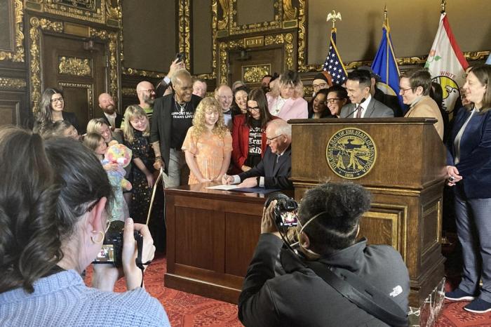Democratic Minnesota Gov. Tim Walz signs an executive order on Wednesday, March 8, 2023, at the State Capitol in St. Paul, Minn., to protect the rights of LGBTQ people from Minnesota and other states to receive gender affirming health care.