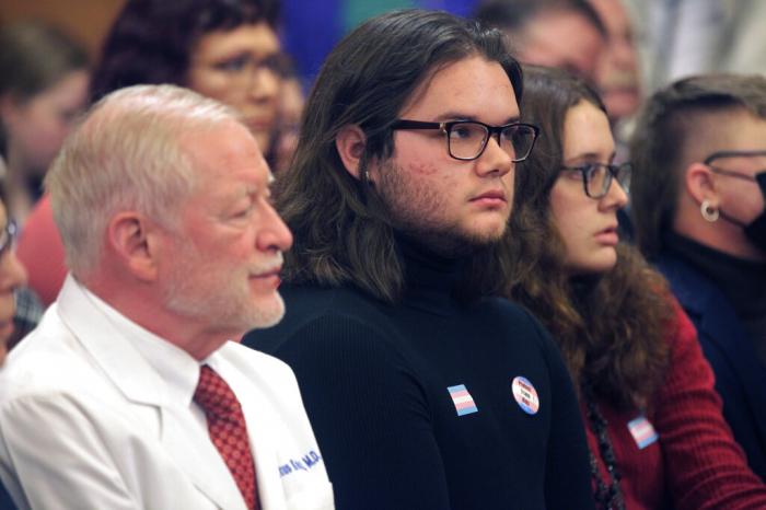 Adam Kellogg, center, a University of Kansas student and transgender man, follows a Kansas Senate health committee hearing on legislation aimed at preventing gender-affirming care for minors, Tuesday, Feb. 14, 2023, at the Statehouse in Topeka, Kan. 