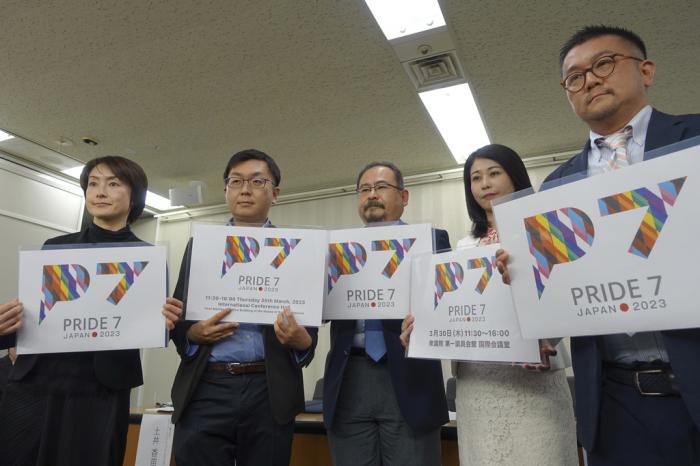 LGBTQ activists hold up cards showing a logo each of their newly founded a civil engagement group Pride7, or P7, for the upcoming Group of Seven Summit that Japan hosts in May, to make policy proposals, including a demand that Japan enact anti-discrimination law to guarantee equal rights for them, at a news conference at the Ministry of Health, Labor and Welfare in Tokyo.