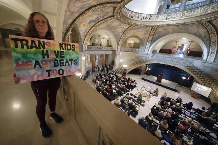 Julia Williams holds a sign in counterprotest during a rally in favor of a ban on gender-affirming health care legislation, Monday, March 20, 2023, at the Missouri Statehouse in Jefferson City, Mo.