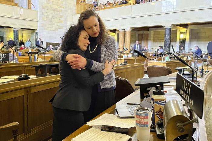 From left, Nebraska Sens. Jen Day and Danielle Conrad hug on the floor of the Nebraska Legislature during emotional debate of a bill that would ban gender-affirming care for anyone 18 and younger in the state on Thursday, March 23, 2023 in Lincoln, Neb.
