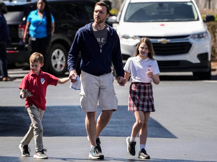 A man walks with children at the Woodmont Baptist Church after a school shooting at The Covenant School, Monday, March 27, 2023, in Nashville, Tenn. (AP Photo/John Bazemore)