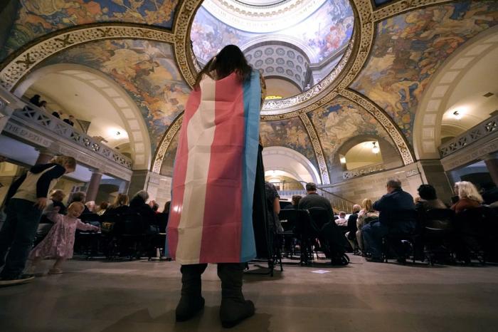 Glenda Starke wears a transgender flag as a counterprotest during a rally in favor of a ban on gender-affirming health care legislation, March 20, 2023, at the Missouri Statehouse in Jefferson City, Mo.