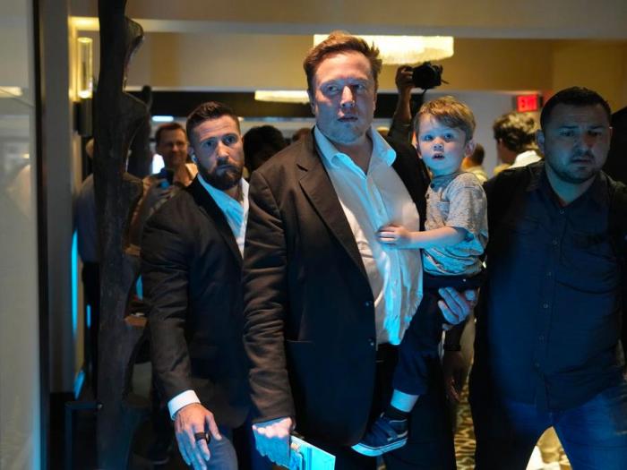 Twitter CEO Elon Musk, center, carries his child as he leaves after speaking at the POSSIBLE marketing conference, Tuesday, April 18, 2023, in Miami Beach, Fla. 