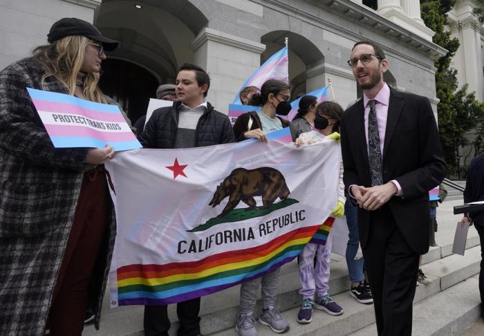 State Sen. Scott Wiener, D-San Francisco, right, prepares to announce his proposed measure to provide legal refuge to displaced transgender youth and their families during a news conference in Sacramento, Calif., on March 17, 2022.