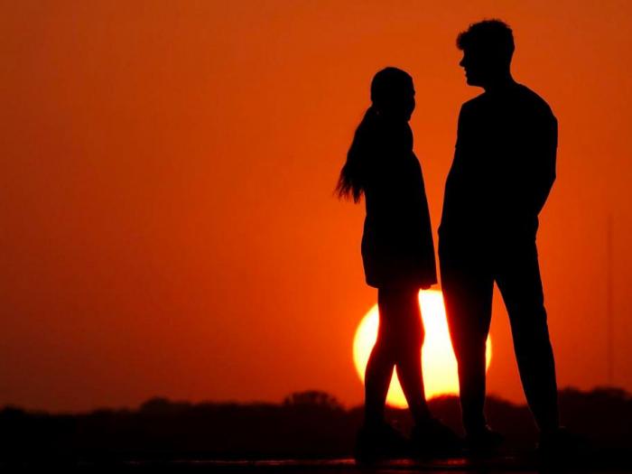 People are silhouetted against the sky as the sun sets Wednesday, May 11, 2022, in Kansas City, Mo. 