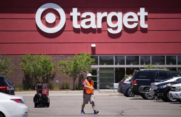 A worker collects shopping carts in the parking lot of a Target store on June 9, 2021, in Highlands Ranch, Colo.