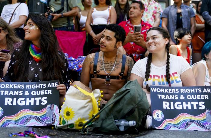 Jessica Garcia, Erik Garcia and Meara White hold signs in support of Starbucks workers as they watch marchers in the annual Seattle Pride Parade, Sunday, June 25, 2023, in Seattle. 