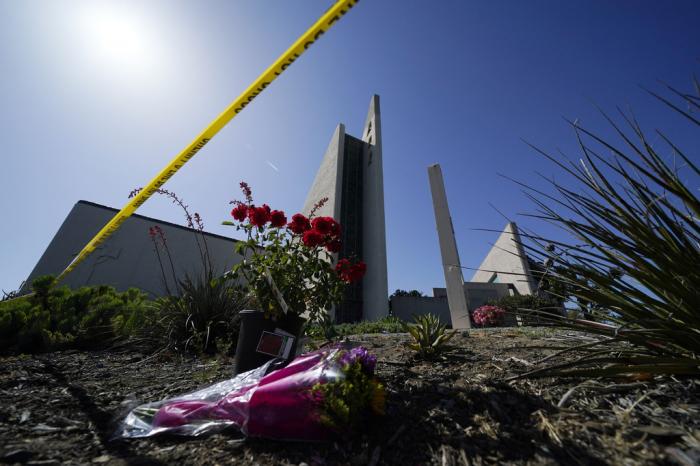 Flowers sit near crime scene tape at Geneva Presbyterian Church on May 17, 2022, in Laguna Woods, Calif., after a fatal shooting hate crime at the church.