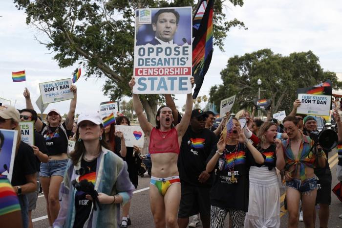 Parade participants carrying signs opposing Gov. Ron DeSantis during the St. Pete Pride Parade along Bayshore Drive on Saturday, June 24, 2023, in St. Petersburg, Fla.